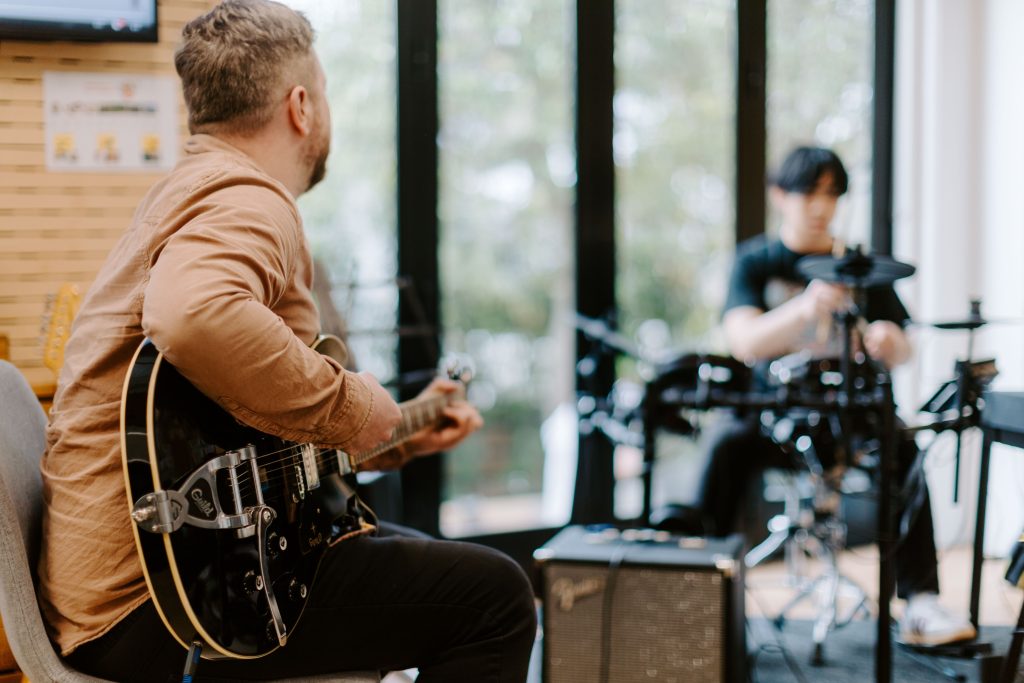 Guitar tutor jamming with a drum student